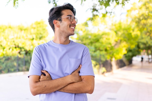 Joven caucásico al aire libre en un parque feliz y sonriente