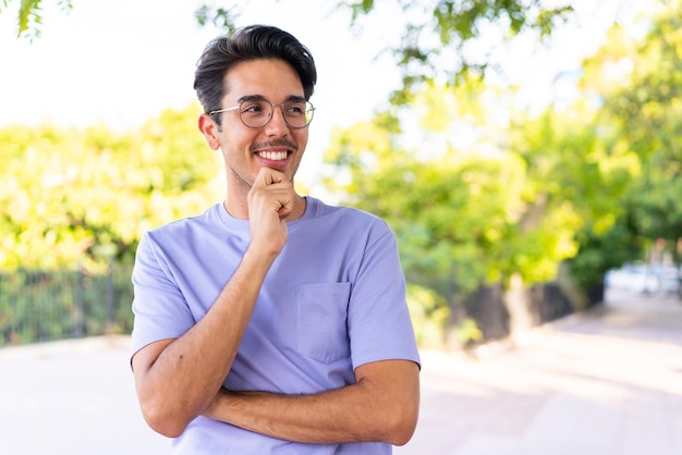 Joven caucásico al aire libre en un parque mirando hacia un lado