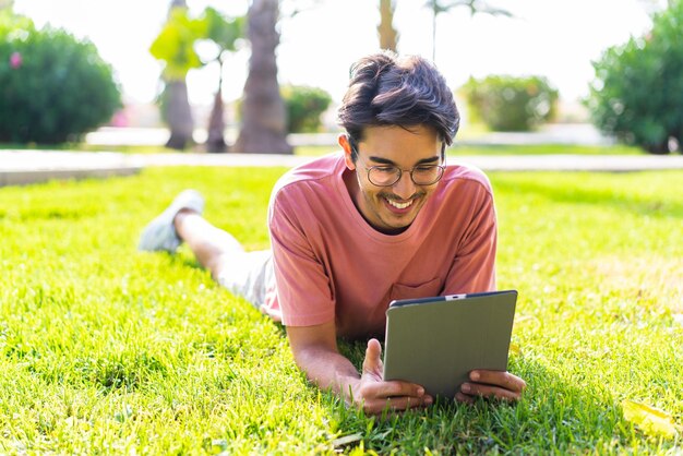 Joven caucásico al aire libre en un parque sosteniendo una tableta