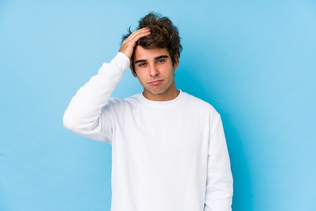 Joven caucásico contra una pared azul aislado cansado y con mucho sueño manteniendo la mano en la cabeza.