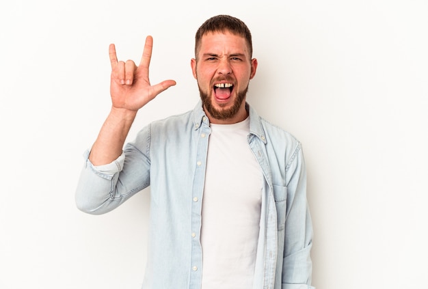 Joven caucásico con diastema aislado sobre fondo blanco mostrando gesto de rock con los dedos