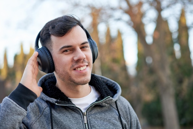 Joven caucásico disfrutando de la música en el parque con los auriculares puestos