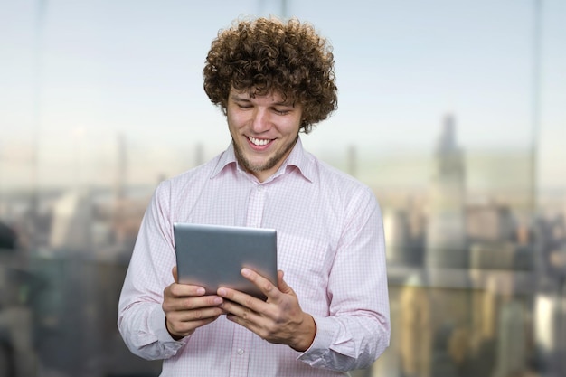 Foto joven caucásico feliz y emocionado con una tableta.