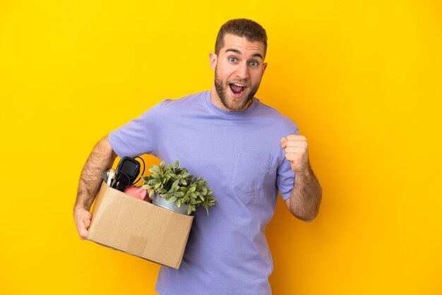 Joven caucásico haciendo un movimiento mientras recoge una caja llena de cosas aisladas