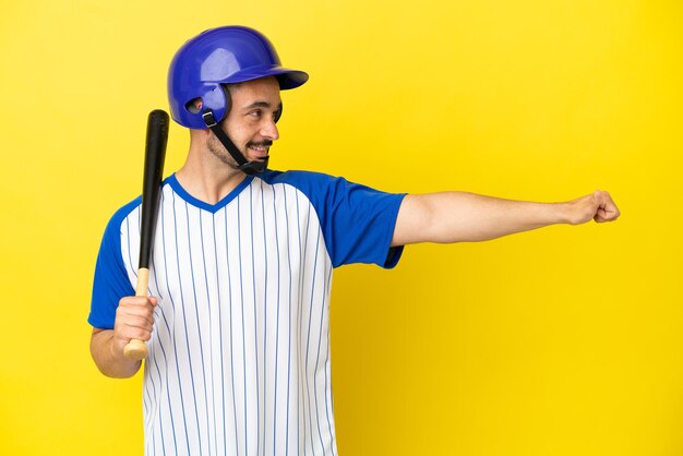 Joven caucásico jugando béisbol aislado sobre fondo amarillo dando un pulgar hacia arriba gesto