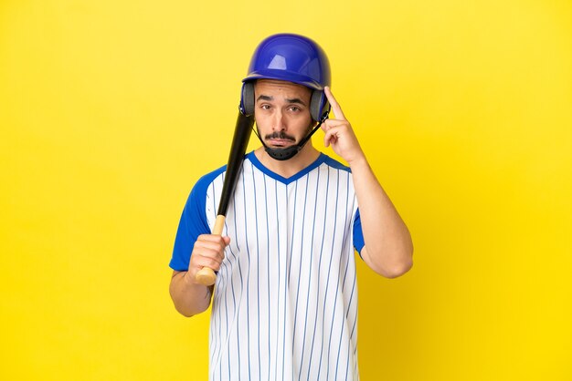 Joven caucásico jugando béisbol aislado sobre fondo amarillo pensando en una idea