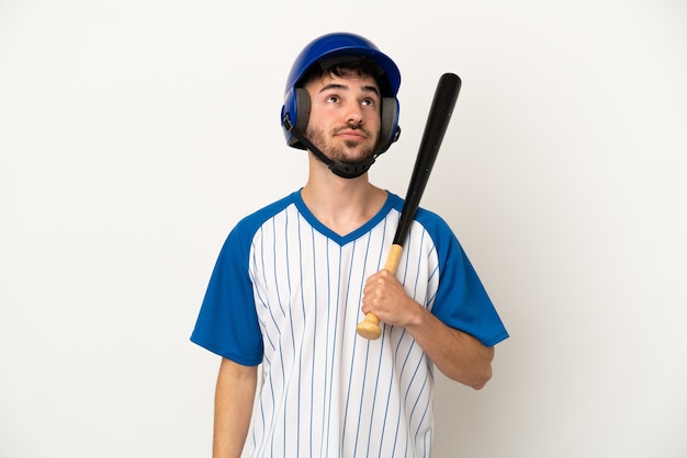 Foto joven caucásico jugando béisbol aislado sobre fondo blanco y mirando hacia arriba