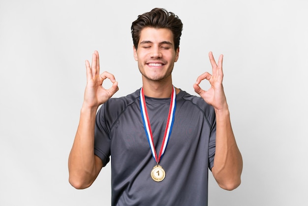 Joven caucásico con medallas sobre fondo blanco aislado en pose zen