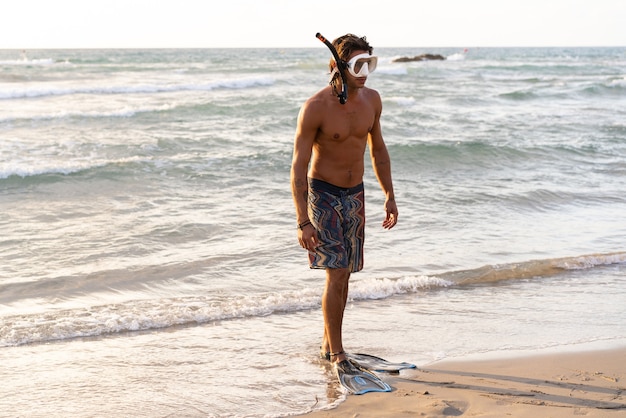 Joven caucásico preparándose para sumergirse en el mar