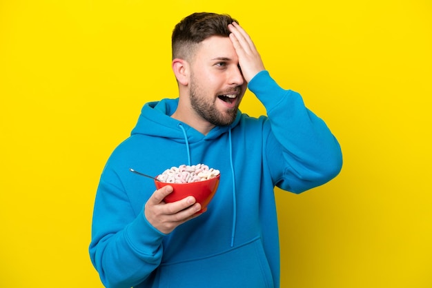 Un joven caucásico que sostiene un tazón de cereales aislado en un fondo amarillo se ha dado cuenta de algo y tiene la intención de encontrar la solución