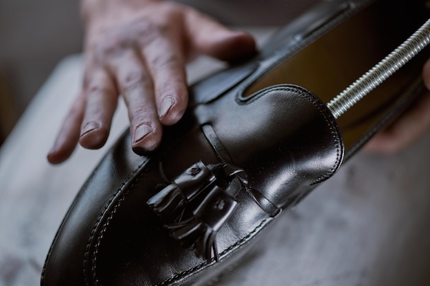 Joven caucásico reparando viejos zapatos de cuero masculinos.