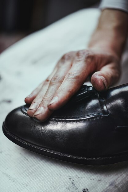 Joven caucásico reparando viejos zapatos de cuero masculinos.