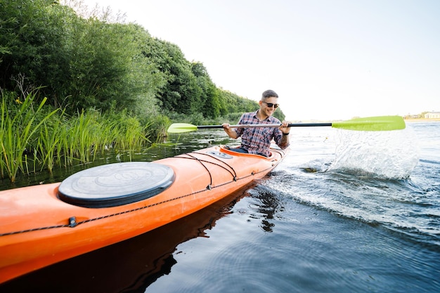 Un joven caucásico se sienta en un kayak y rema El concepto de entretenimiento acuático