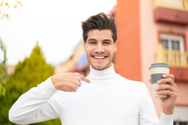 Joven caucásico sosteniendo un café para llevar al aire libre con expresión facial sorpresa