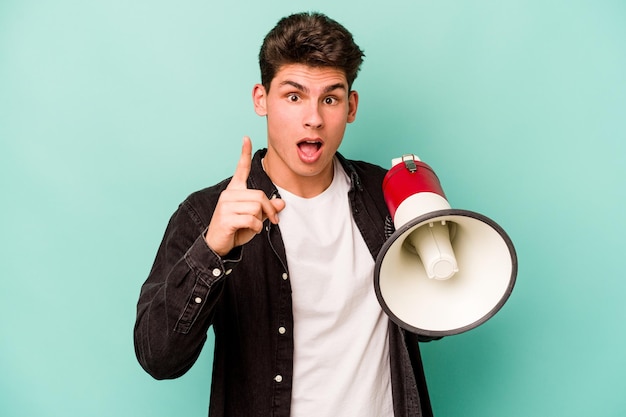 Joven caucásico sosteniendo un megáfono aislado de fondo blanco con un concepto de inspiración de ideas