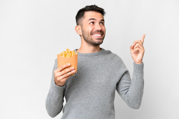 Foto joven caucásico sosteniendo patatas fritas sobre fondo blanco aislado señalando una gran idea