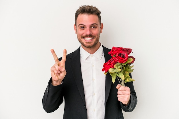 Joven caucásico sosteniendo un ramo de flores aislado de fondo blanco mostrando el número dos con los dedos.