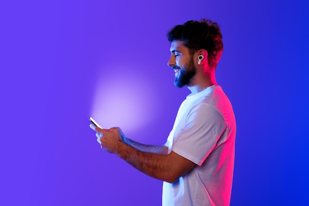 Foto un joven caucásico sostiene el teléfono disfrutando de la música a través de auriculares de estudio