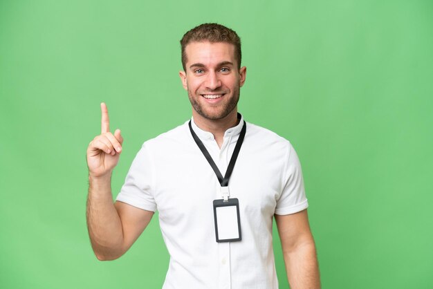 Joven caucásico con tarjeta de identificación aislada en un fondo de croma verde que señala una gran idea