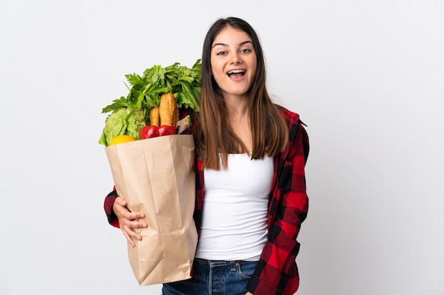 Joven caucásico con verduras aislado en blanco con expresión facial sorpresa