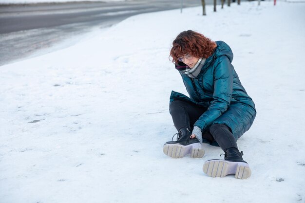 Foto una joven cayó en la nieve y se torció el tobillo.