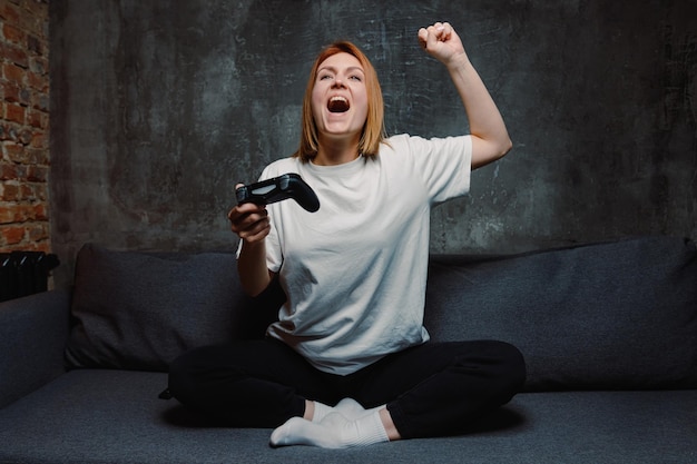 Una joven celebra su victoria en un videojuego Juegos online desde casa durante la pandemia