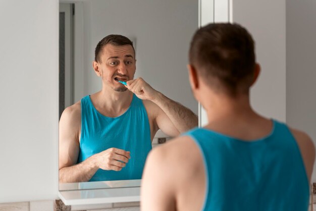 Joven se cepilla los dientes en el baño frente al espejo Higiene bucal Rutina matutina