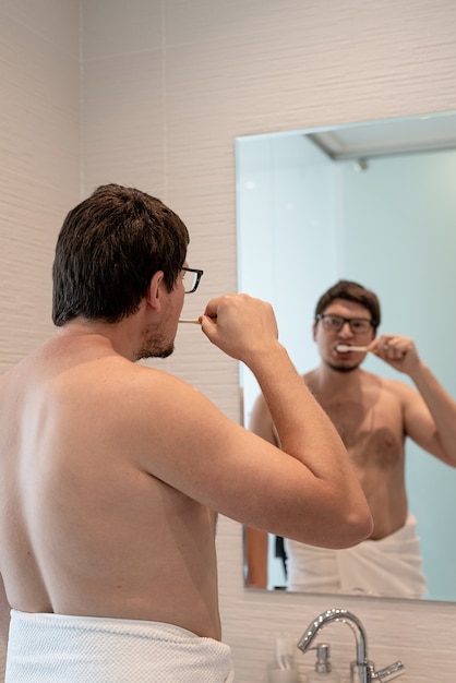 Un joven cepillándose los dientes en el baño.