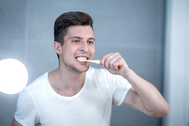 Joven cepillándose los dientes en el baño.