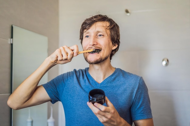 Foto joven cepillándose los dientes con carbón activado en polvo para cepillarse y blanquear los dientes cepillo ecológico de bambú