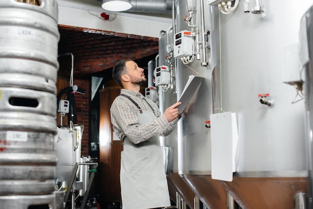 Un joven cervecero barbudo monitorea las lecturas del sensor durante el proceso de elaboración. Haciendo cerveza.