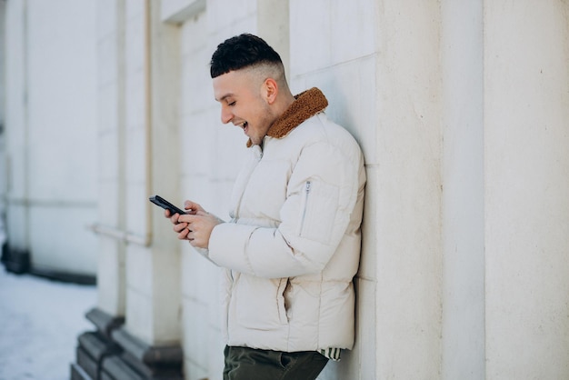 Joven con chaqueta de invierno usando el teléfono fuera de la calle