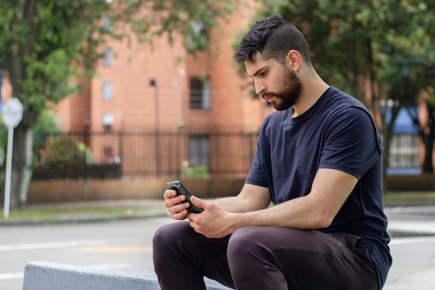 Un joven charlando con su teléfono celular en un parque en la calle de una ciudad.