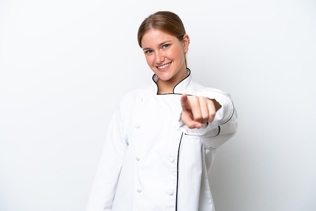 Una joven chef aislada de fondo blanco te señala con una expresión de confianza