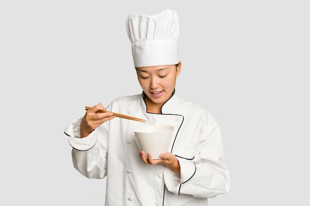 Joven chef asiática mujer preparando fideos aislados