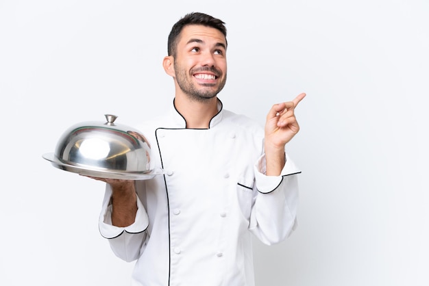 Joven chef con bandeja aislado sobre fondo blanco apuntando a una gran idea