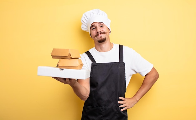 Joven chef con bigote con comida rápida para llevar