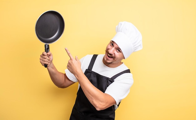 Joven chef con bigote y una sartén.