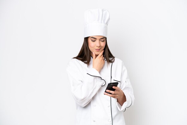 Joven chef brasileña aislada de fondo blanco pensando y enviando un mensaje