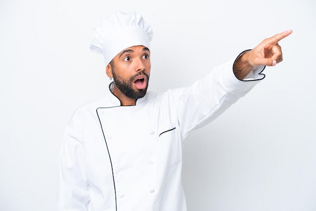 Joven chef brasileño aislado de fondo blanco apuntando hacia otro lado