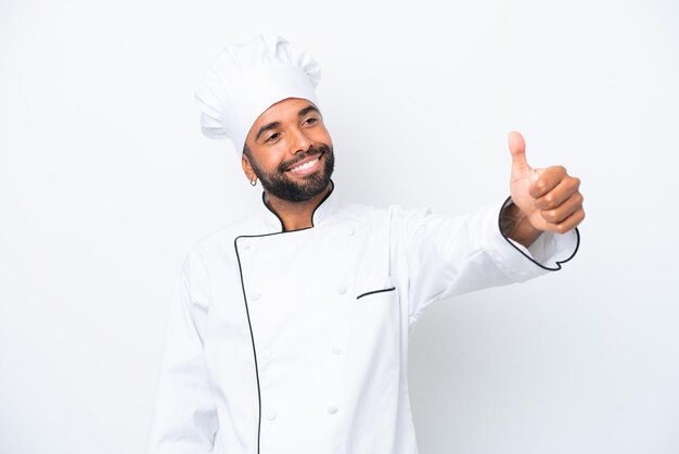 Joven chef brasileño aislado de fondo blanco dando un gesto de pulgar hacia arriba