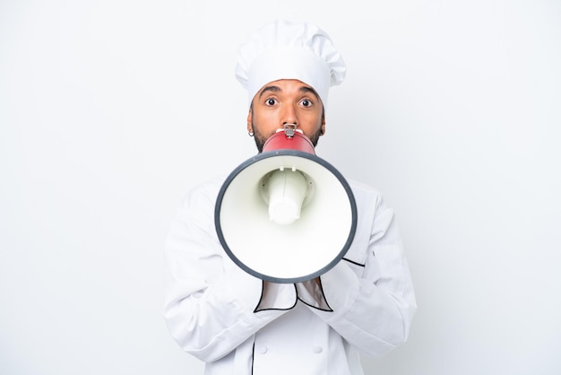 Joven chef brasileño aislado de fondo blanco gritando a través de un megáfono