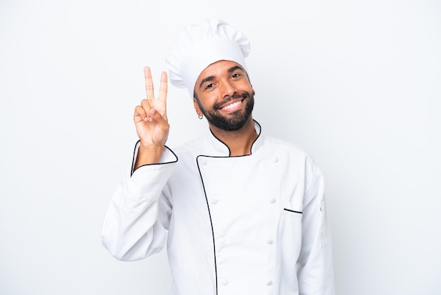 Joven chef brasileño aislado de fondo blanco sonriendo y mostrando el signo de la victoria