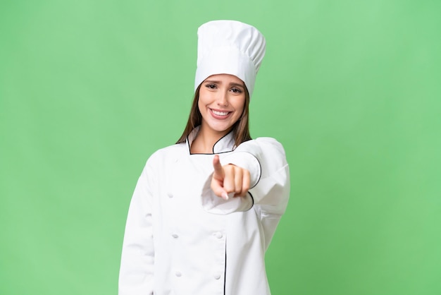 Una joven chef caucásica sobre un fondo aislado te señala con una expresión de confianza