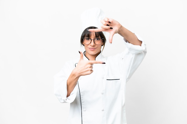 Foto joven chef caucásico sobre fondo blanco aislado enfocando la cara símbolo de encuadre