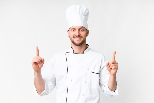 Joven chef caucásico sobre un fondo blanco aislado señalando una gran idea