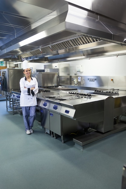 Joven chef feliz parado al lado de la superficie de trabajo