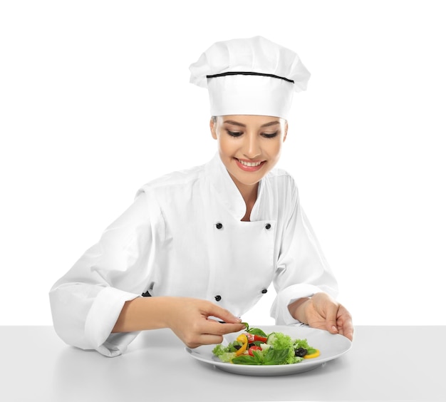 Joven chef haciendo ensalada sobre fondo blanco.