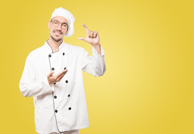 Joven chef haciendo un gesto de pequeño tamaño con su mano