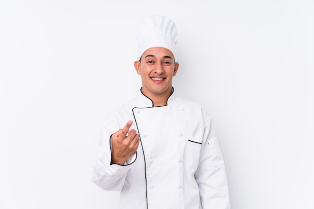 Joven chef latino hombre apuntando con el dedo